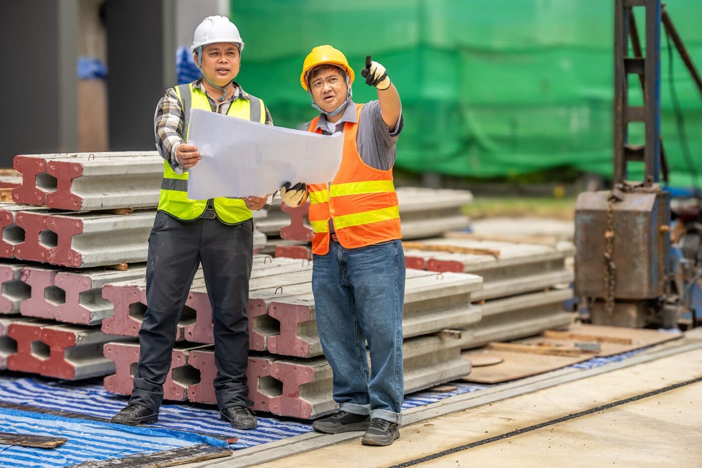 Two contractors reviewing building plans on a job site